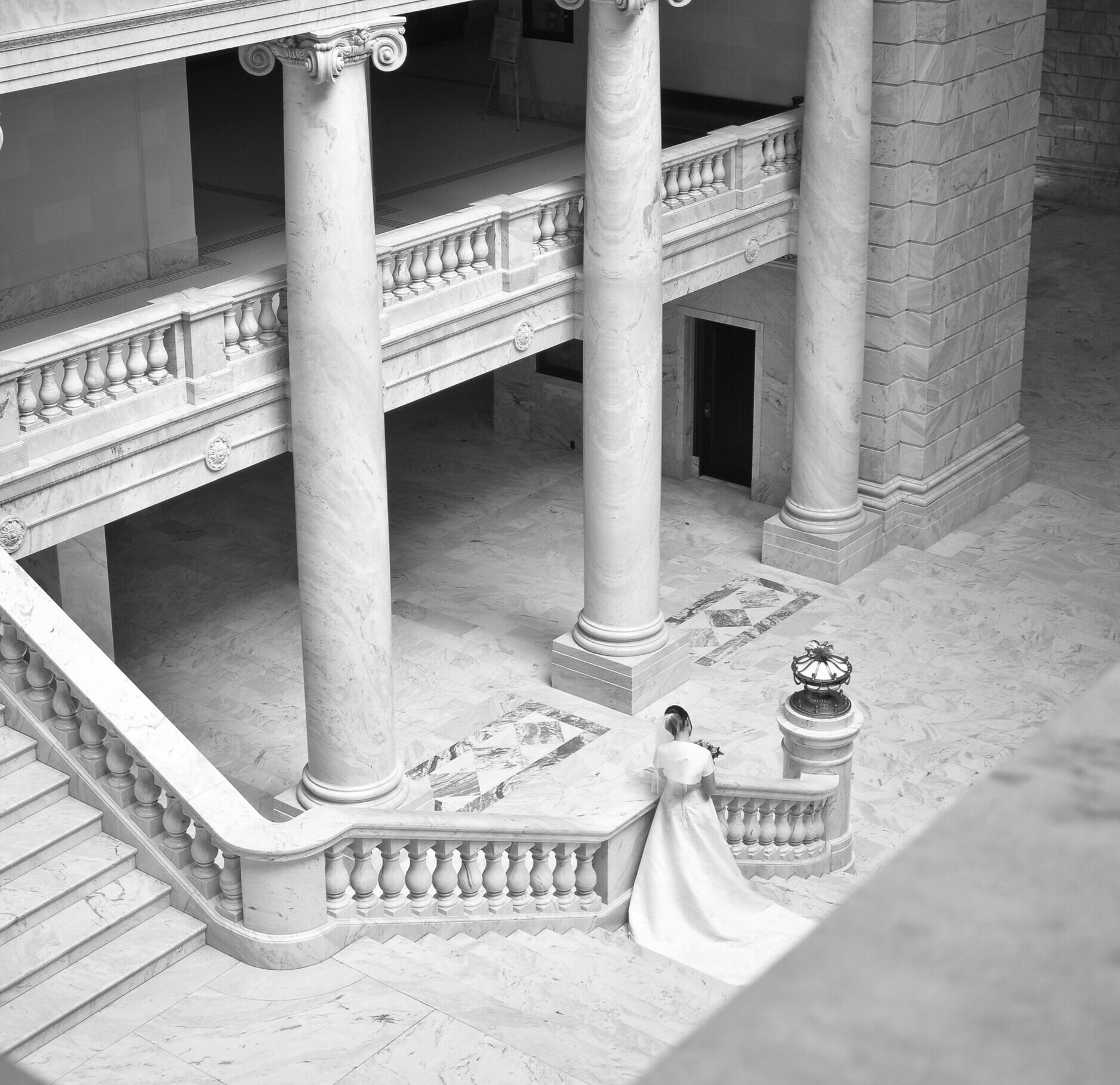 Bride standing at base of grand neoclassical staircase at Cotswolds wedding venue