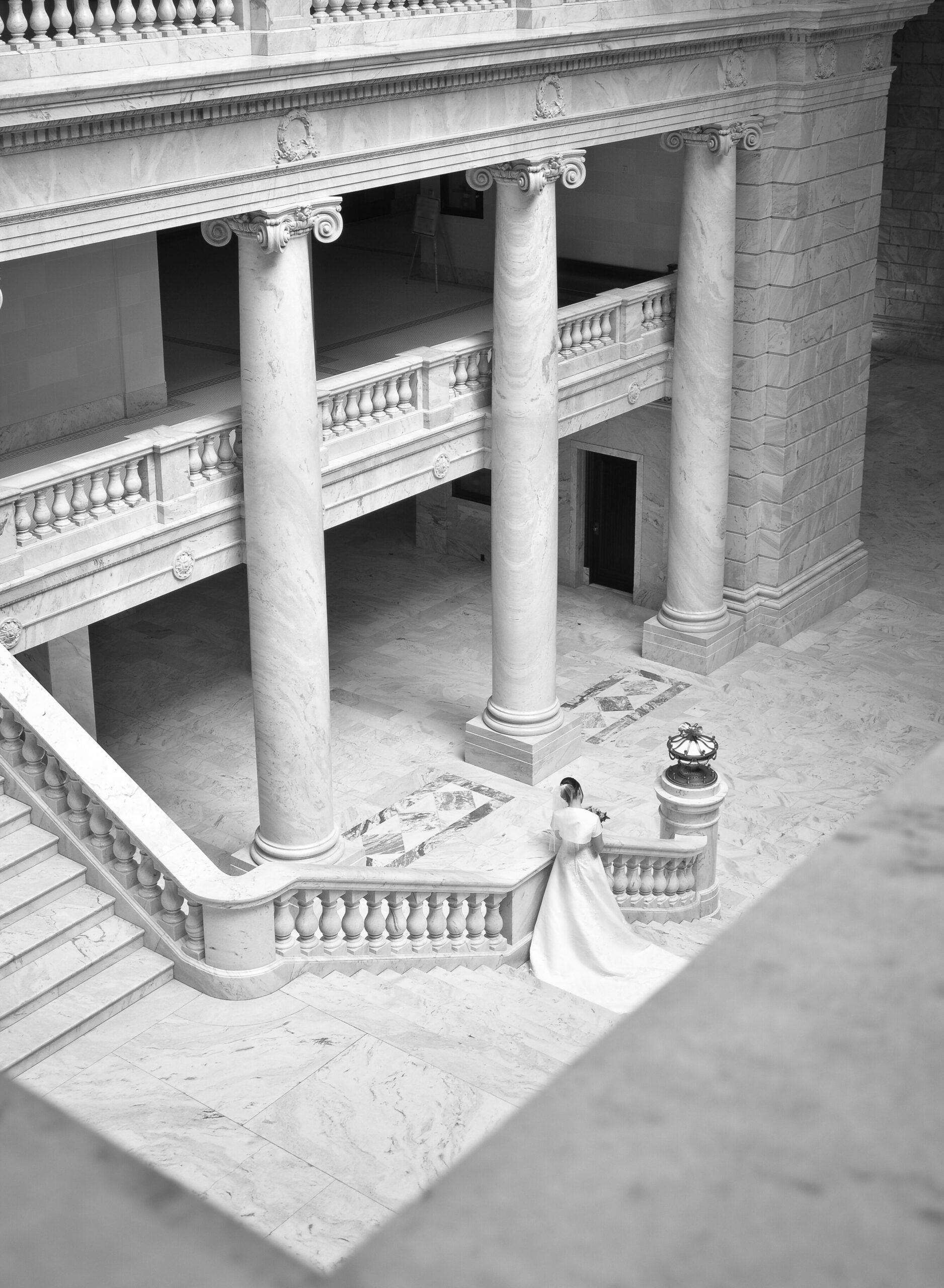 Bride standing at base of grand neoclassical staircase at Cotswolds wedding venue